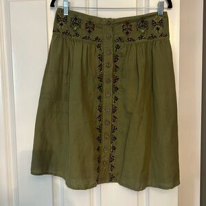Maeve green, pleated front, button-down embroidered skirt with wood buttons